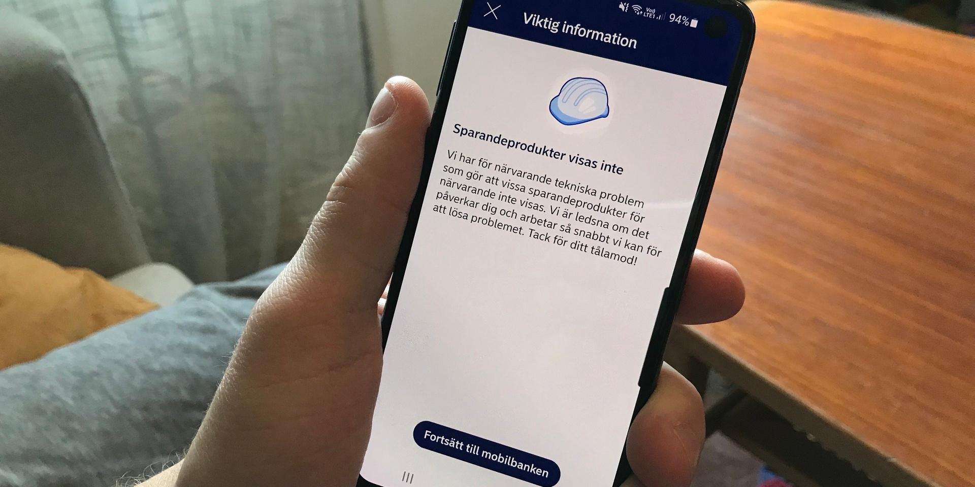 En manshand håller i en mobiltelefon och det är ett felmeddelande uppe på skärmen. Felmeddelandet har rubriken ”Sparandeprodukter visas inte”.